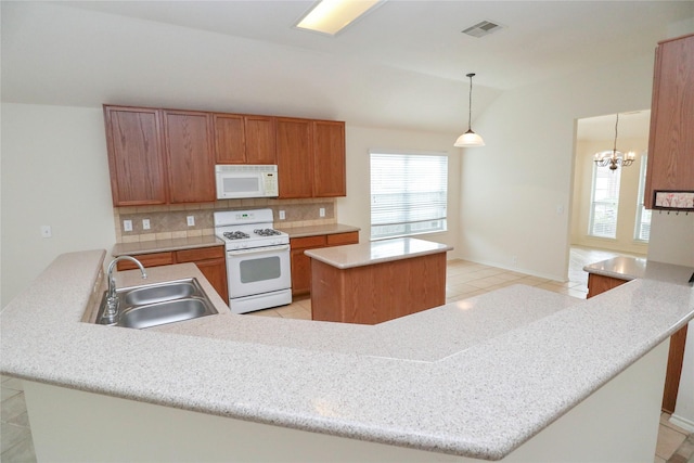 kitchen featuring decorative light fixtures, sink, a center island, kitchen peninsula, and white appliances