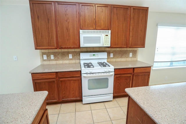 kitchen with white appliances, light stone countertops, decorative backsplash, and light tile patterned floors