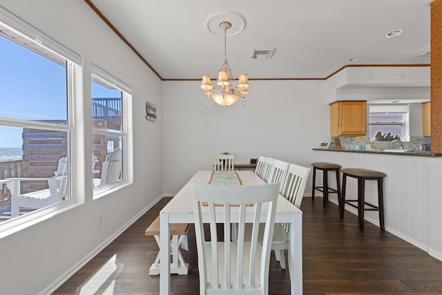 dining room featuring dark hardwood / wood-style flooring, crown molding, sink, and a chandelier