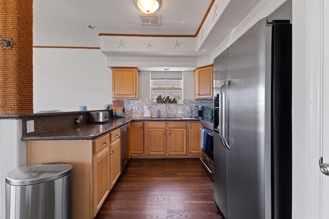 kitchen featuring appliances with stainless steel finishes, sink, dark hardwood / wood-style flooring, dark stone counters, and kitchen peninsula