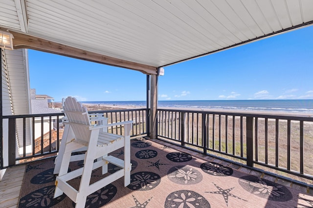 wooden terrace featuring a water view and a view of the beach