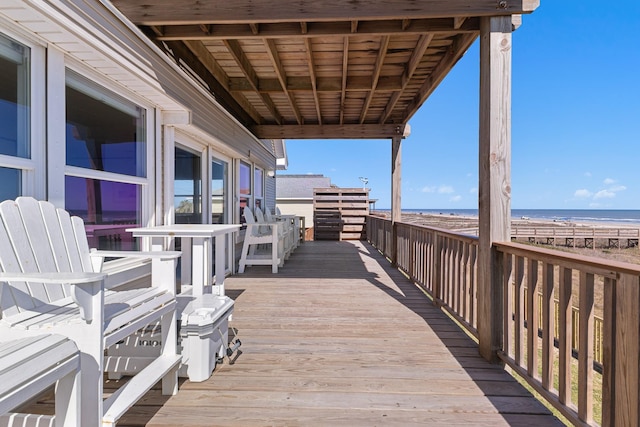 wooden deck with a beach view and a water view