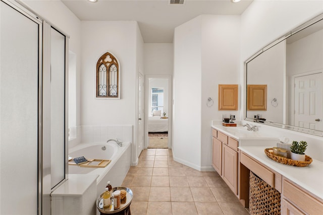 bathroom with a relaxing tiled tub, tile patterned floors, and vanity