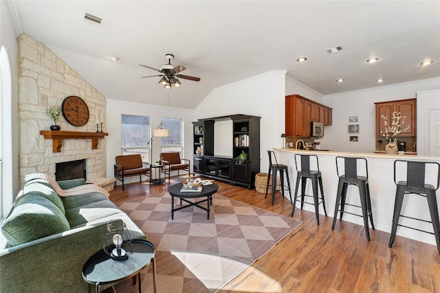 living room featuring crown molding, vaulted ceiling, dark hardwood / wood-style floors, ceiling fan, and a fireplace