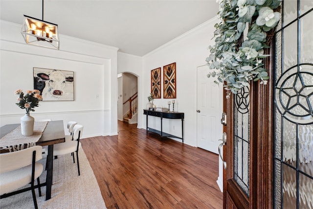 foyer entrance with crown molding, dark wood-type flooring, and a notable chandelier