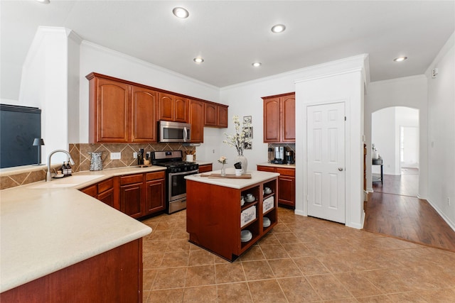 kitchen with sink, tasteful backsplash, crown molding, a center island, and stainless steel appliances