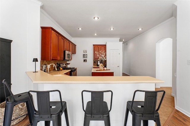 kitchen with crown molding, appliances with stainless steel finishes, backsplash, and kitchen peninsula