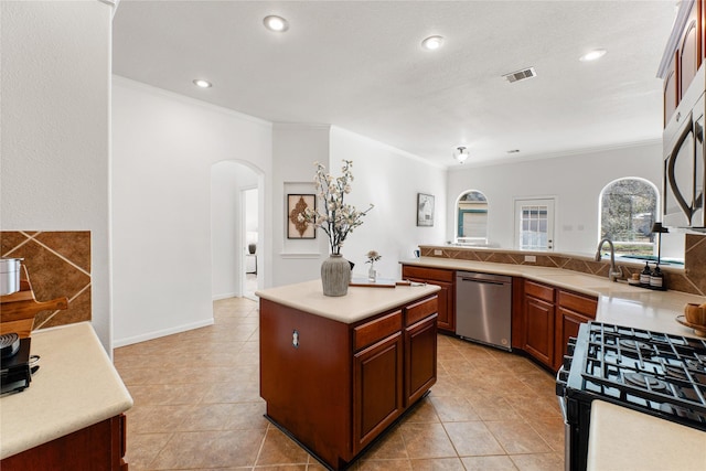 kitchen with gas stove, sink, crown molding, stainless steel dishwasher, and a kitchen island