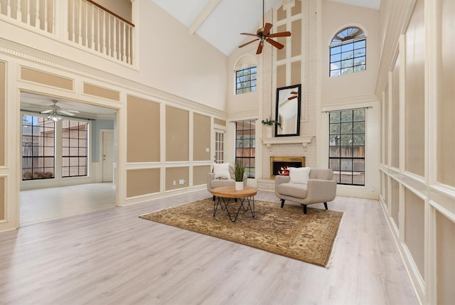 living area featuring ceiling fan, a brick fireplace, and light wood-type flooring