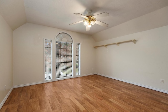 empty room featuring ceiling fan, vaulted ceiling, and light wood-type flooring