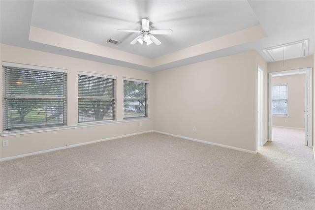 carpeted spare room featuring ceiling fan and a tray ceiling