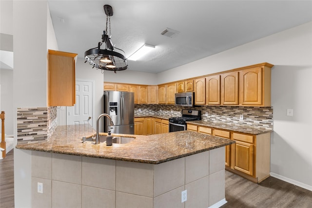 kitchen with pendant lighting, sink, hardwood / wood-style flooring, stainless steel appliances, and light stone counters