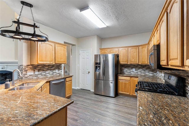 kitchen featuring tasteful backsplash, sink, dark stone counters, light hardwood / wood-style floors, and stainless steel appliances