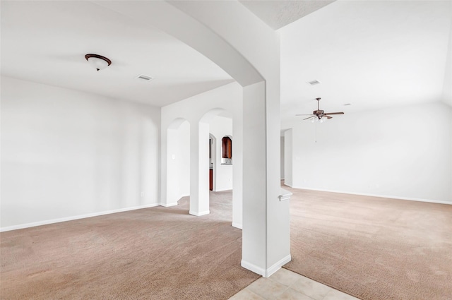 spare room featuring light carpet, visible vents, arched walkways, baseboards, and ceiling fan