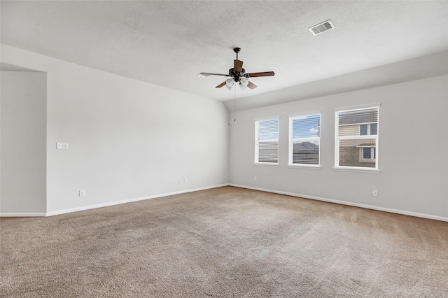 carpeted spare room with a ceiling fan, visible vents, a textured ceiling, and baseboards