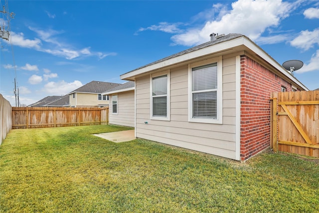 rear view of house featuring a yard, brick siding, and a fenced backyard