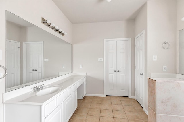 bathroom with a closet, tile patterned flooring, vanity, and baseboards