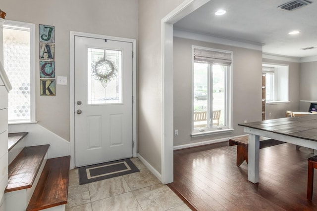 foyer entrance with crown molding and light wood-type flooring