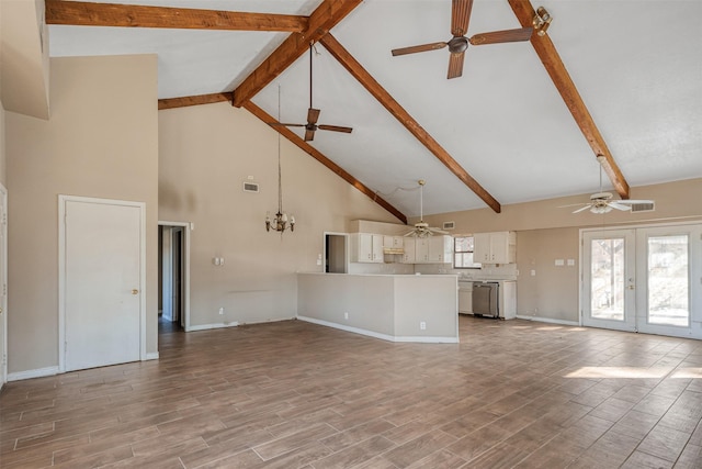 unfurnished living room with beam ceiling, ceiling fan with notable chandelier, high vaulted ceiling, and french doors