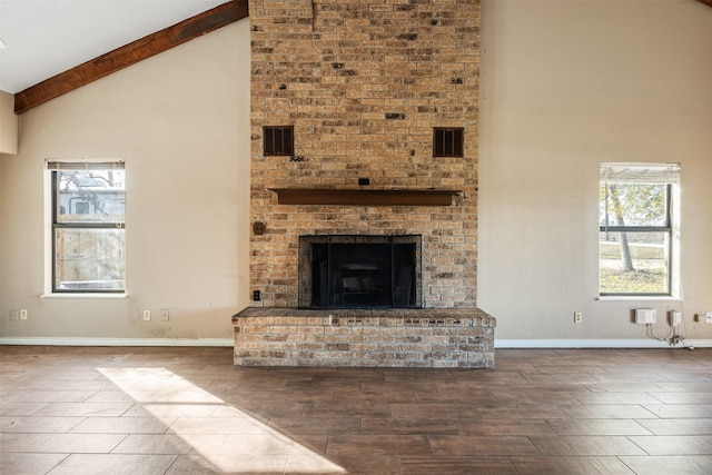 unfurnished living room with beam ceiling, a fireplace, high vaulted ceiling, and a healthy amount of sunlight