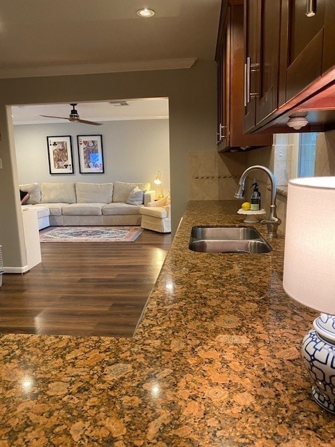 kitchen featuring sink, crown molding, ceiling fan, dark stone countertops, and backsplash