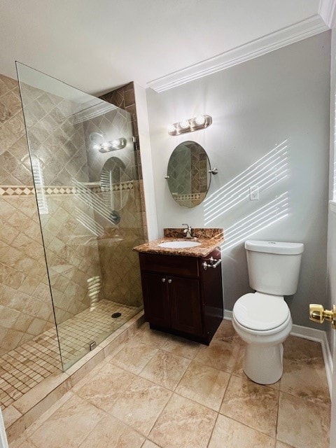 bathroom with ornamental molding, toilet, vanity, and a tile shower