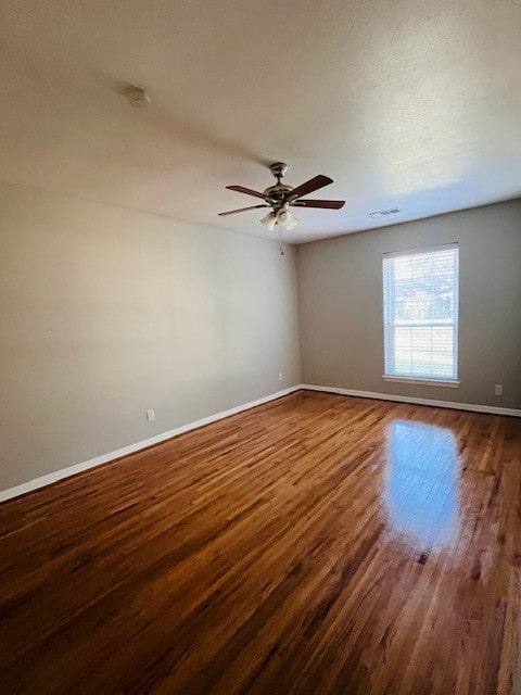 spare room with dark wood-type flooring and ceiling fan