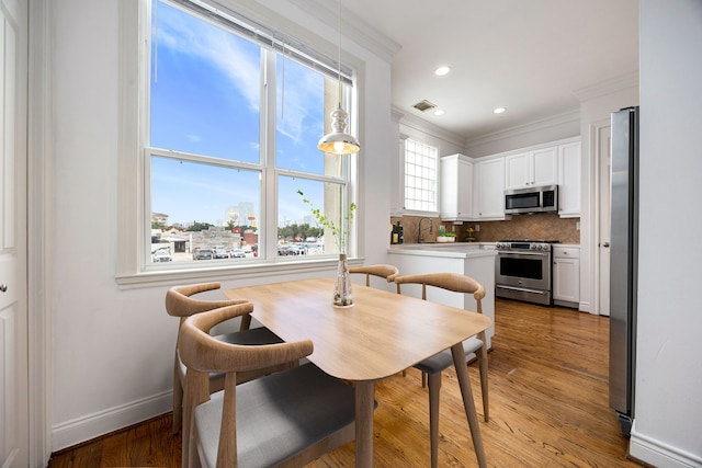 dining area featuring hardwood / wood-style flooring, ornamental molding, and sink