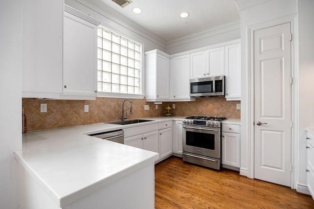 kitchen with light wood-type flooring, appliances with stainless steel finishes, sink, and white cabinets