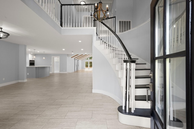 stairway featuring an inviting chandelier and a towering ceiling