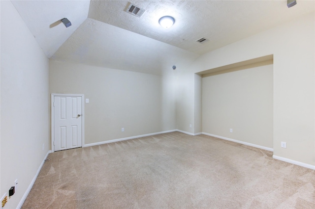 additional living space featuring vaulted ceiling, light colored carpet, and a textured ceiling