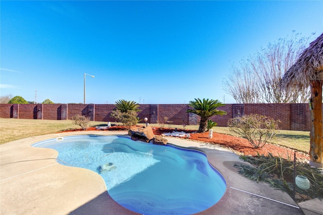 view of swimming pool with a fenced backyard and a lawn