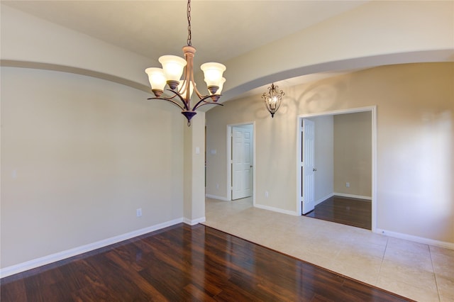 spare room with hardwood / wood-style flooring and a notable chandelier