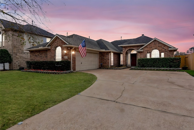 single story home featuring a garage and a lawn