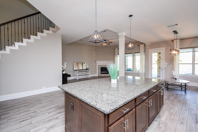 kitchen featuring pendant lighting, a fireplace, a center island, and ceiling fan