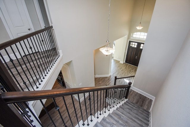 stairs featuring a towering ceiling and wood-type flooring