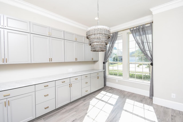 kitchen with ornamental molding, light hardwood / wood-style flooring, an inviting chandelier, and decorative light fixtures