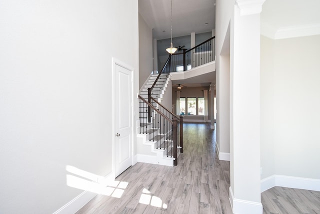 foyer featuring crown molding, a towering ceiling, ceiling fan, and light hardwood / wood-style floors