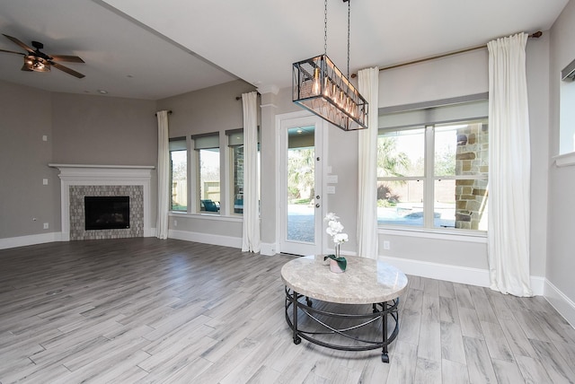 interior space with a tiled fireplace, ceiling fan with notable chandelier, and light hardwood / wood-style floors