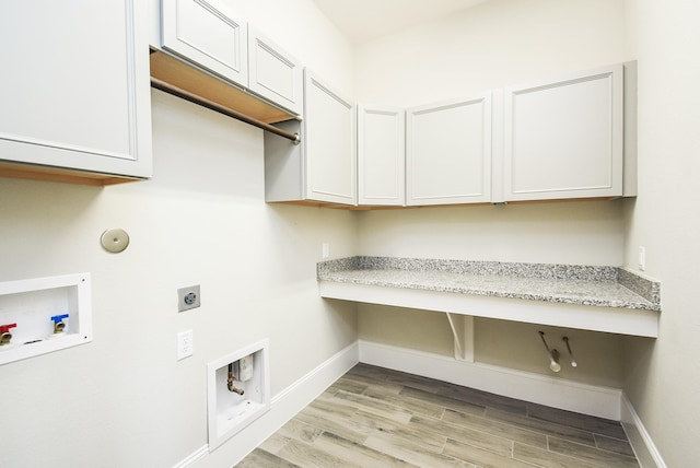 clothes washing area featuring gas dryer hookup, light hardwood / wood-style flooring, cabinets, washer hookup, and hookup for an electric dryer