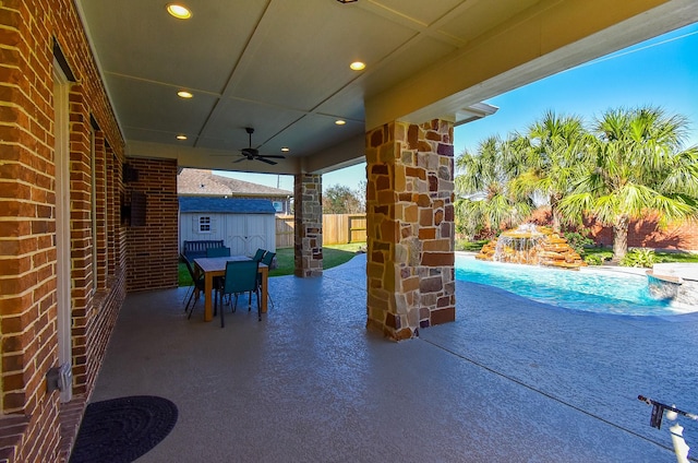 view of patio / terrace featuring a fenced in pool, ceiling fan, and a storage unit