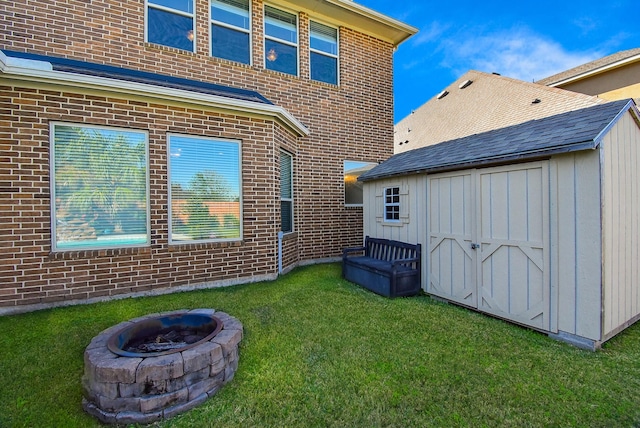 back of house with a storage shed, an outdoor fire pit, and a lawn