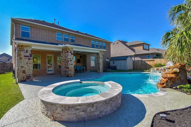 view of pool featuring an in ground hot tub, pool water feature, a patio area, and a shed