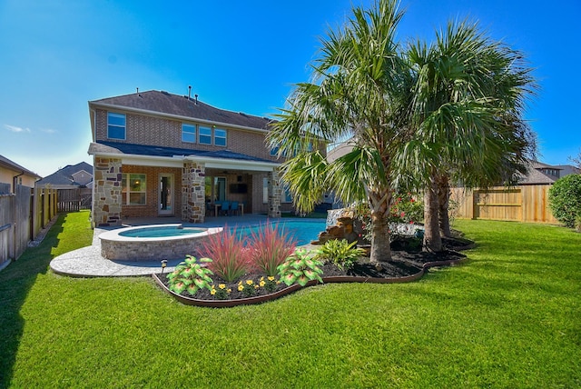 rear view of house featuring a swimming pool with hot tub, a patio area, and a lawn