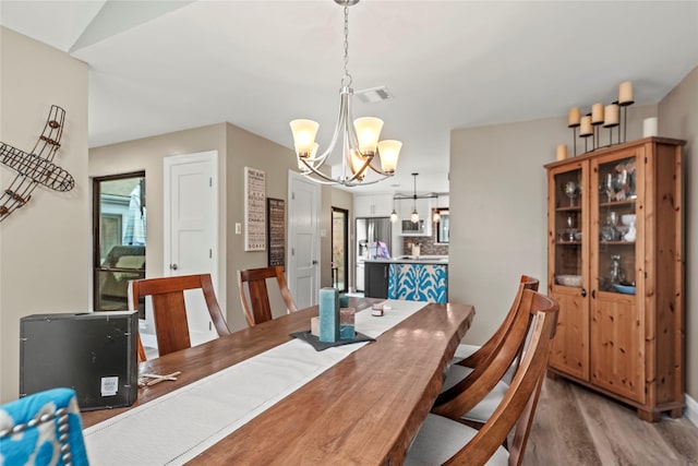 dining space featuring wood-type flooring and a chandelier