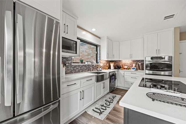 kitchen featuring appliances with stainless steel finishes, sink, white cabinets, decorative backsplash, and dark wood-type flooring