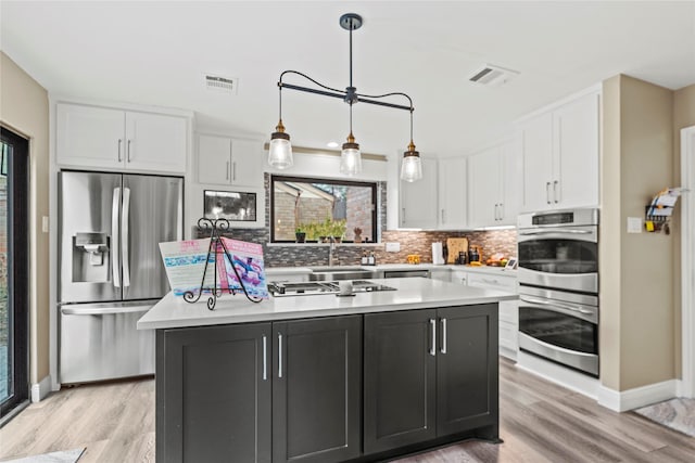 kitchen featuring white cabinetry, stainless steel appliances, decorative backsplash, a kitchen island, and decorative light fixtures