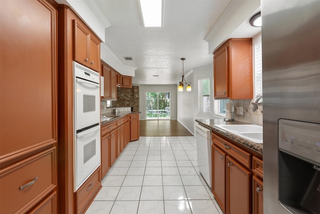 kitchen with decorative light fixtures, sink, light tile patterned floors, crown molding, and white appliances