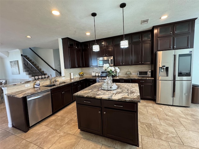 kitchen featuring pendant lighting, appliances with stainless steel finishes, sink, and a kitchen island