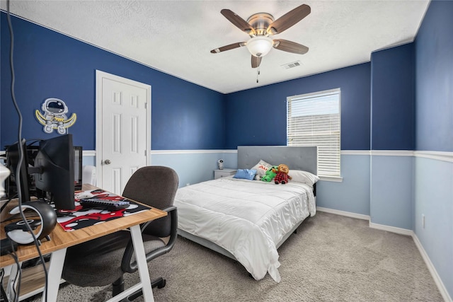 carpeted bedroom featuring a ceiling fan, baseboards, visible vents, and a textured ceiling